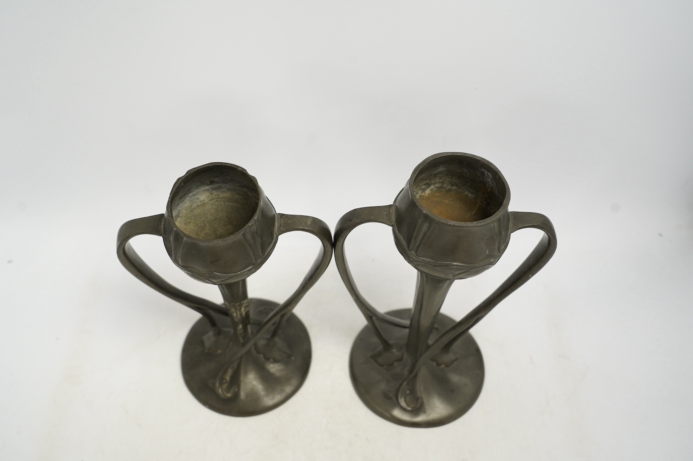 A pair of Art Nouveau Liberty Tudric pewter twin-handled vases, stamped to the bases, 25cm high. Condition - one good, the other poor to fair